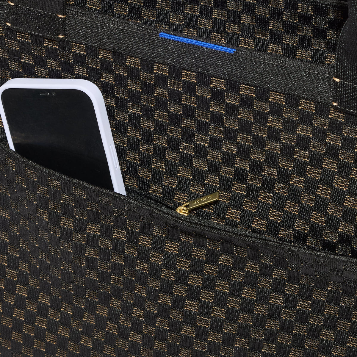 A close up of The Zip Travel Tote in Night Song with a phone slipped into the outer pocket.