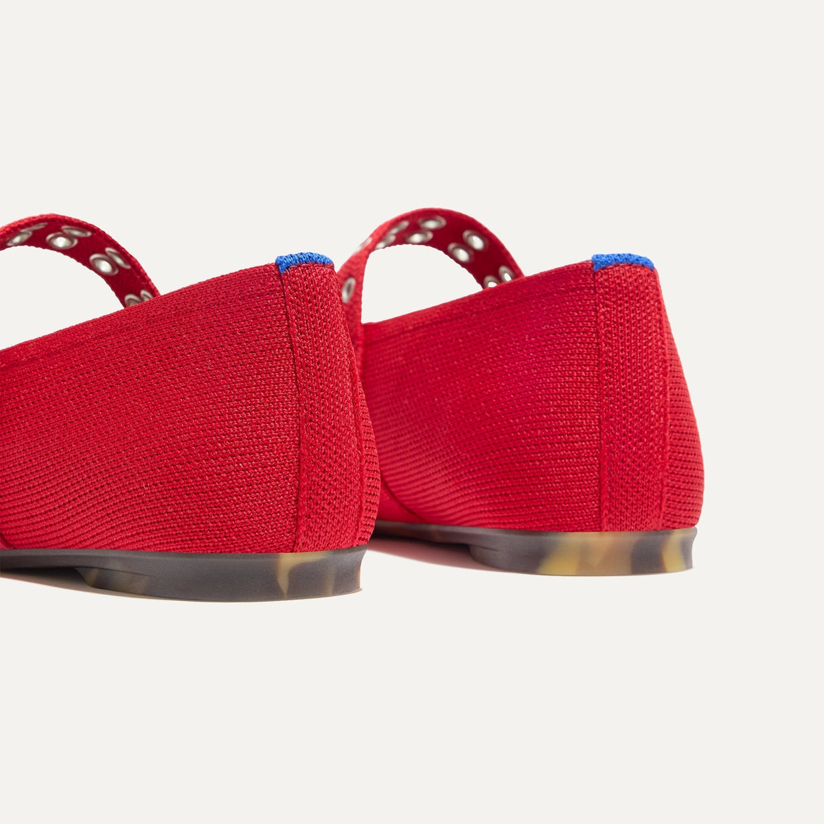 Close up of the heel of The Max Buckle Mary Jane in Cherry, with Rothy's signature blue halo.